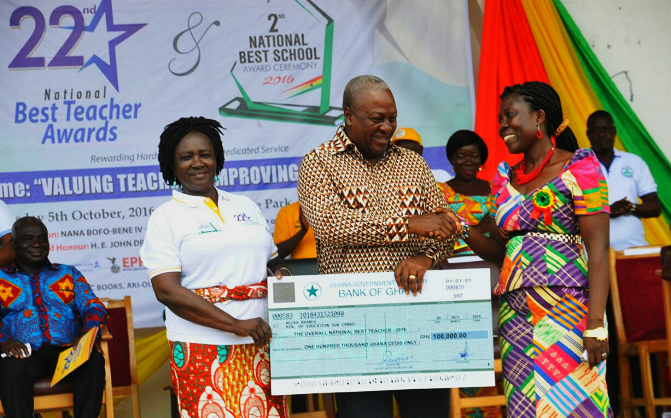 President Mahama presenting a cheque for GH¢100,000 to Madam Oppong for being adjudged the overall best teacher. 